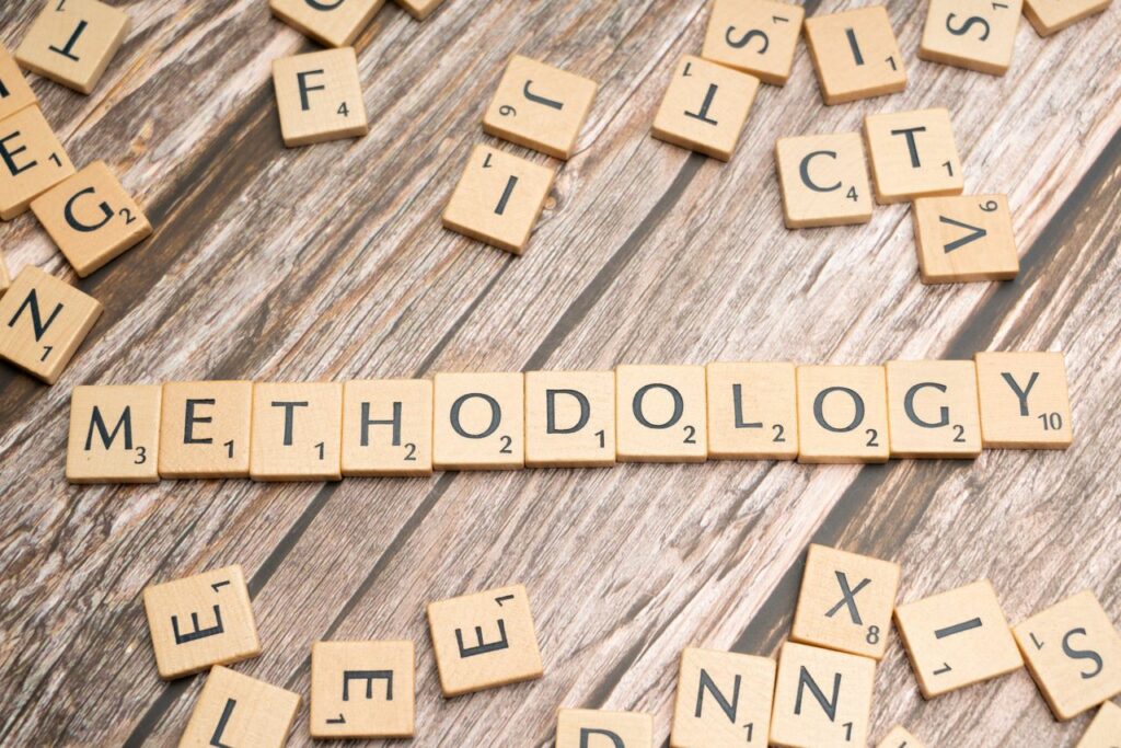 Wooden letter tiles spelling 'methodology' on a textured wooden surface, emphasizing research.