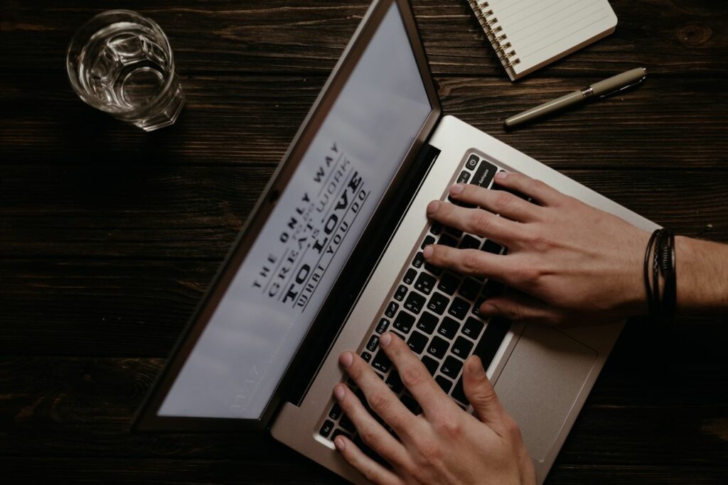 Hands on a laptop with an inspirational quote displayed on the screen, shot from above.